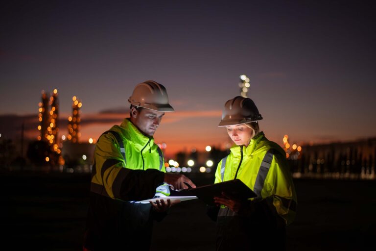 Two workers with high-visibility vests working near power